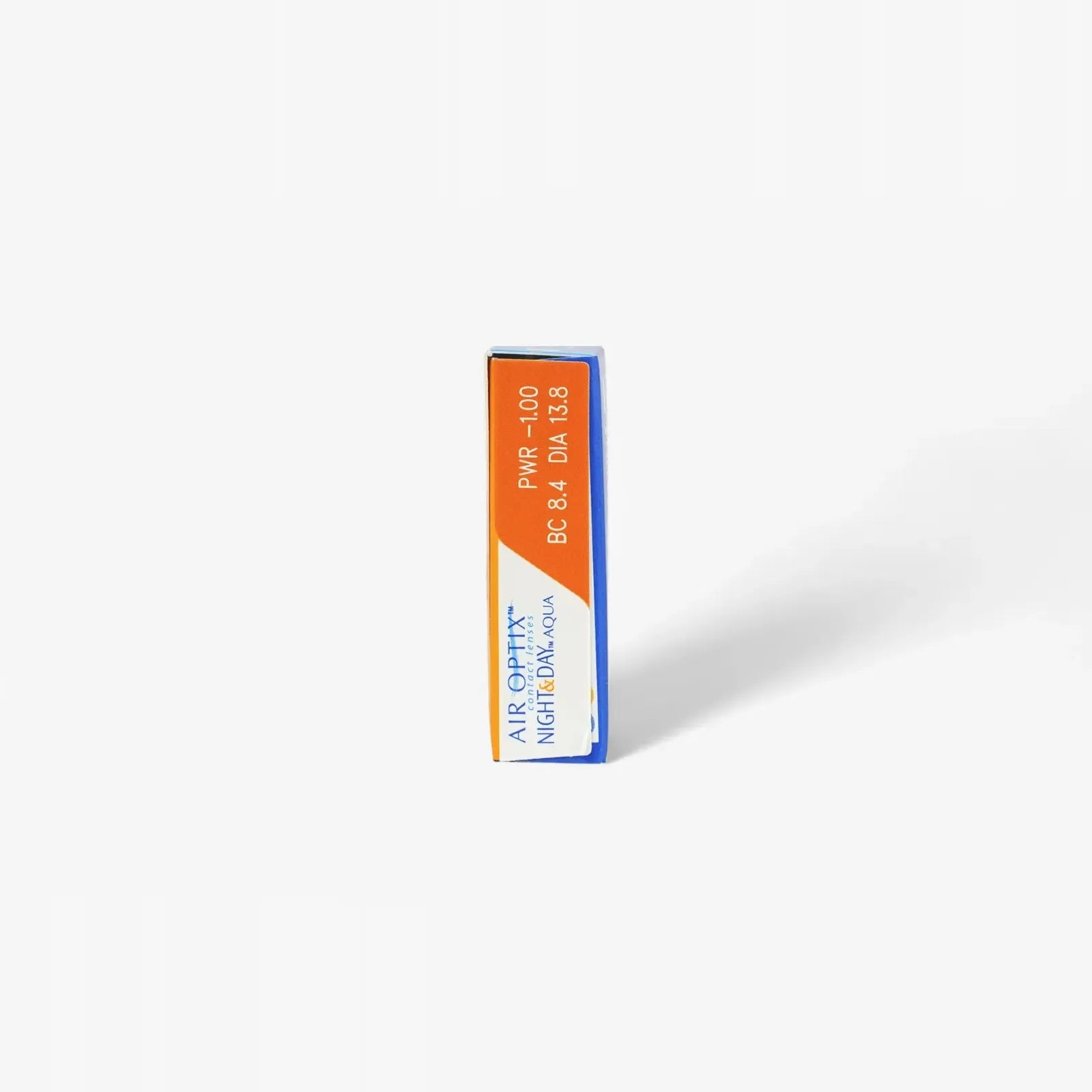 A rectangular box of Air Optix Night & Day - 6 Pack contact lenses stands upright on a white background, displaying orange and blue labeling with product information visible on the side.