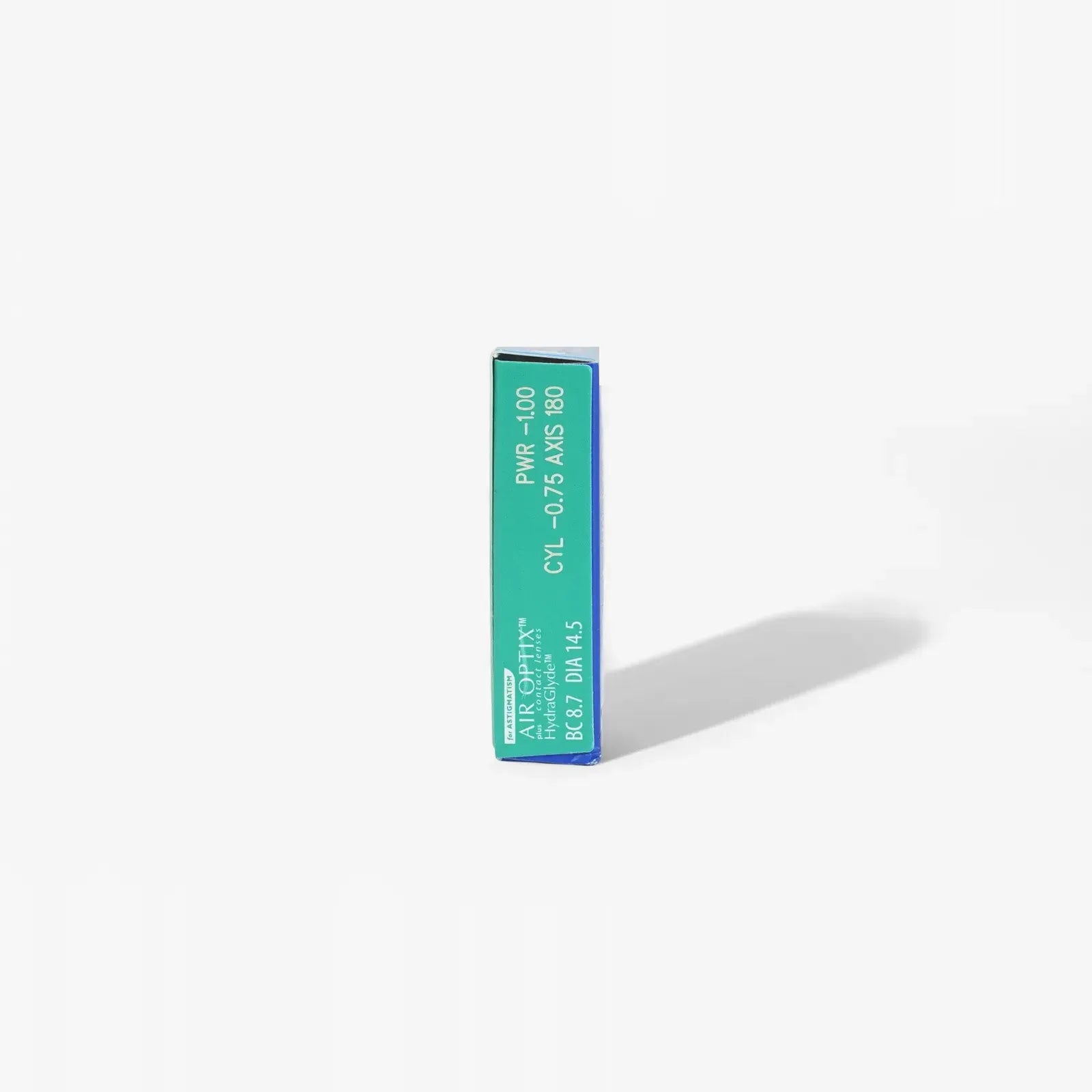 A rectangular green and blue Air Optix Hydraglyde For Astig 6Pk box stands upright on a white background, casting a faint right shadow. The design features text and codes on the front, echoing signature brand packaging elements.