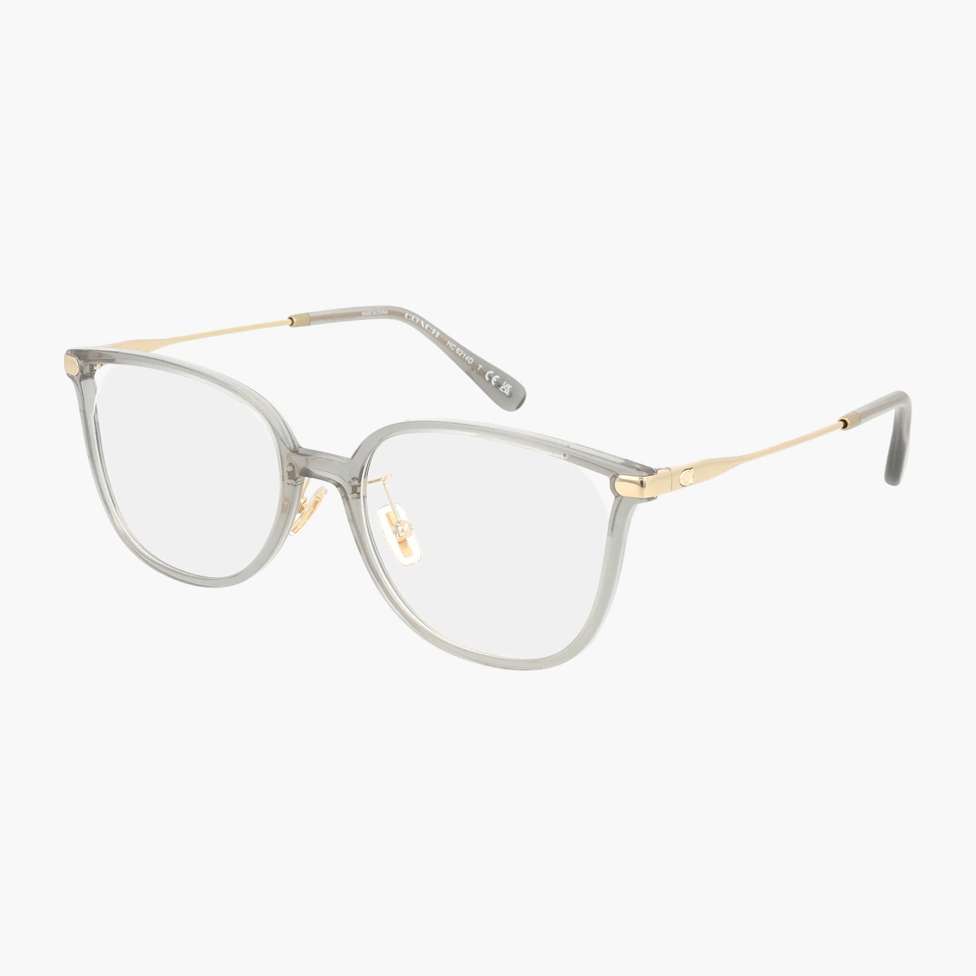 The HC6214D features round clear lenses, a transparent gray acetate frame, thin gold metal arms, and adjustable nose pads in a modern minimalist design against a white background.
