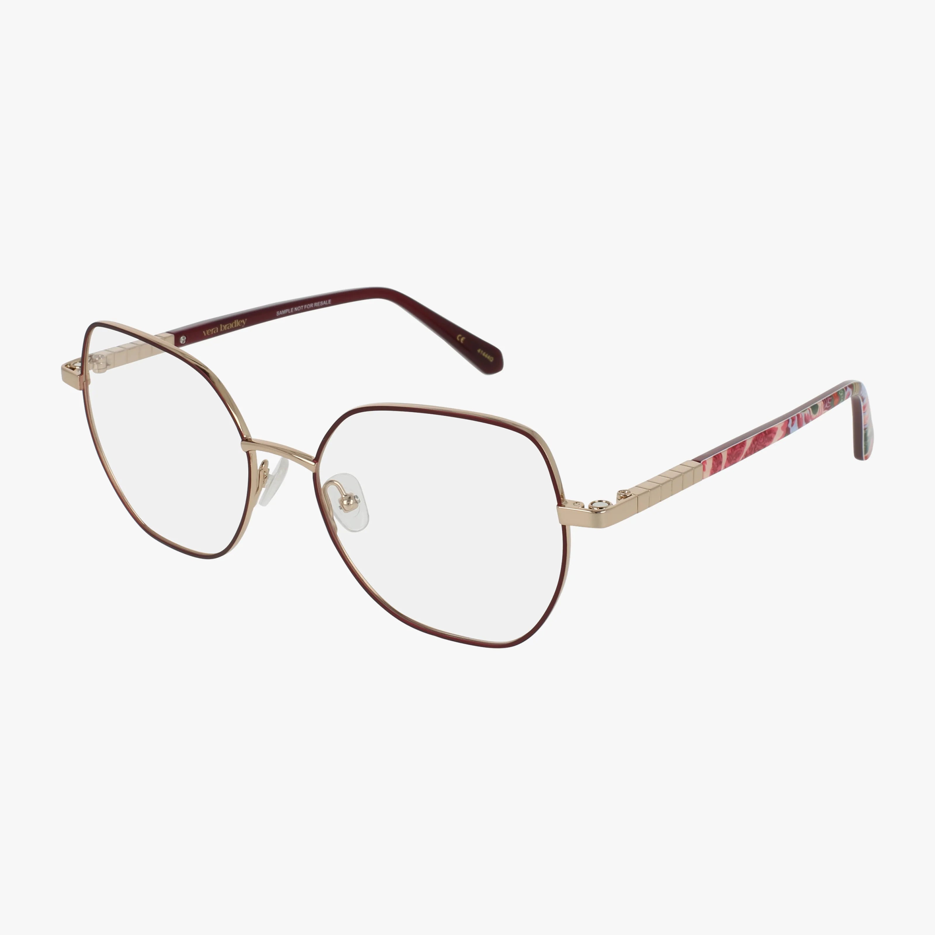 FIORA eyeglasses feature thin gold metal frames, slightly geometric lenses, and maroon temple arms with a decorative side pattern.