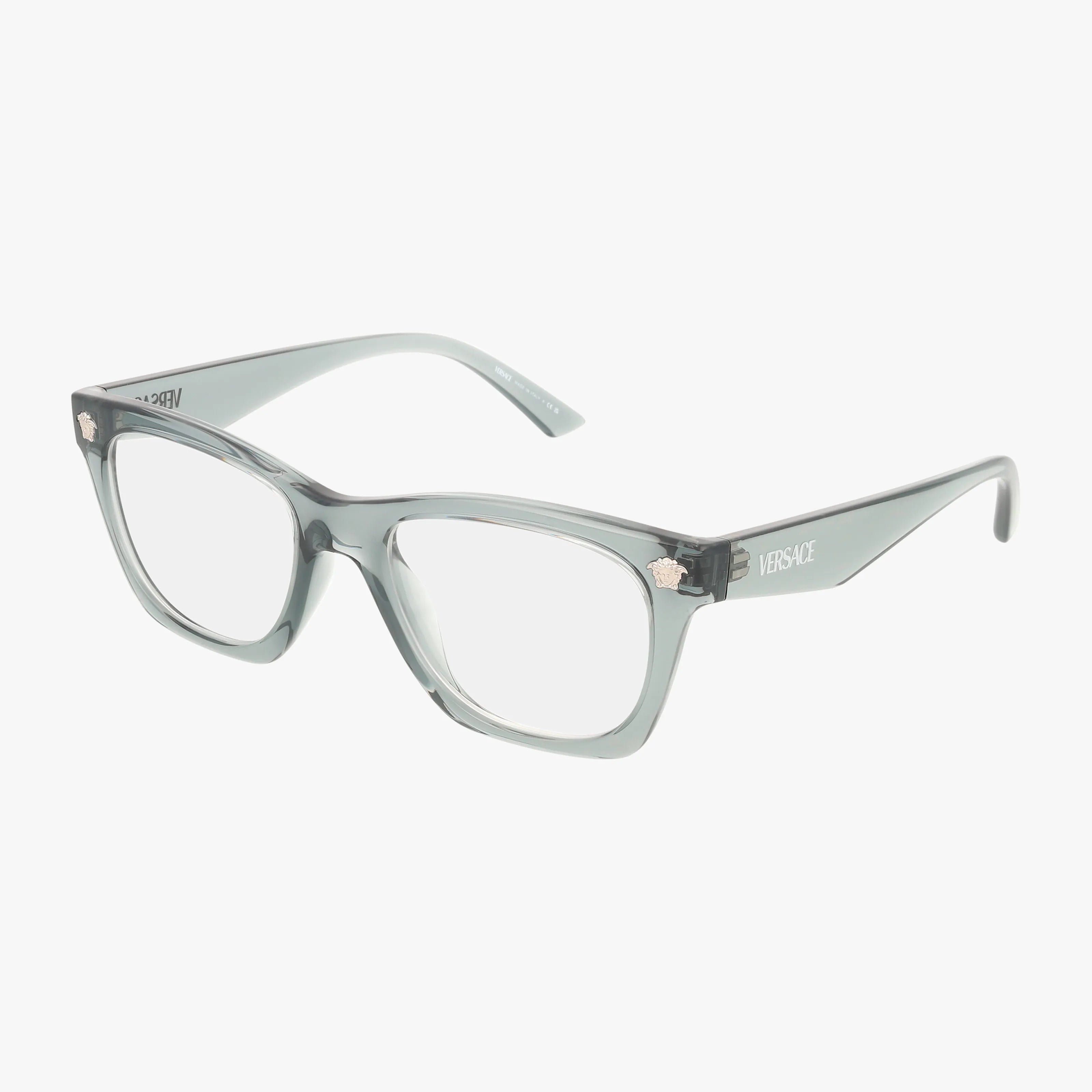 The Versace VE3363U eyeglasses feature a translucent gray polished frame with square clear lenses. The temples display the brand name and Medusa logo, combining style and durability. Shown against a white background.
