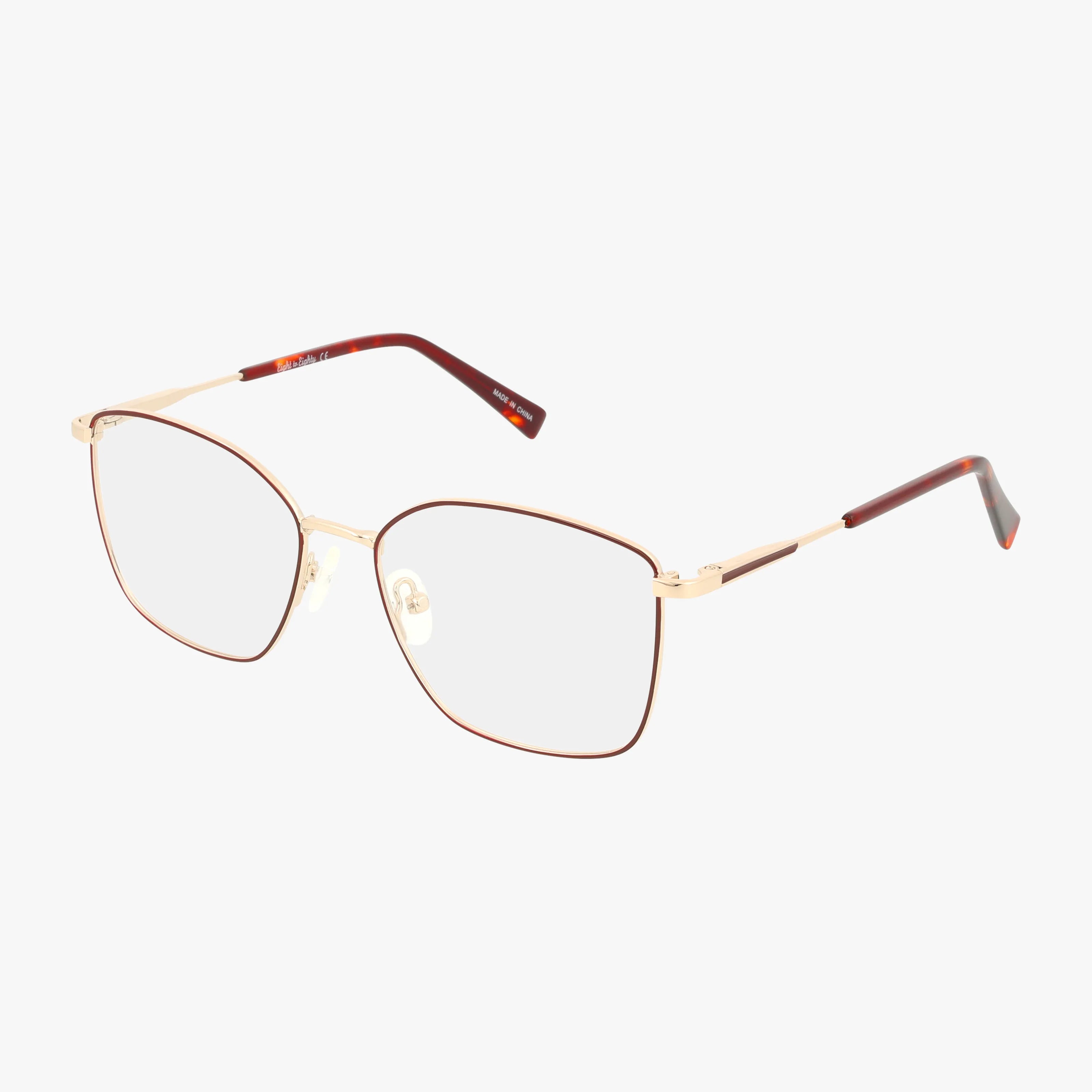 GOLDIE eyeglasses feature thin gold metal frames with square lenses, gold temples with brown tips, and clear nose pads, all shown on a plain white background for a distinctive style.