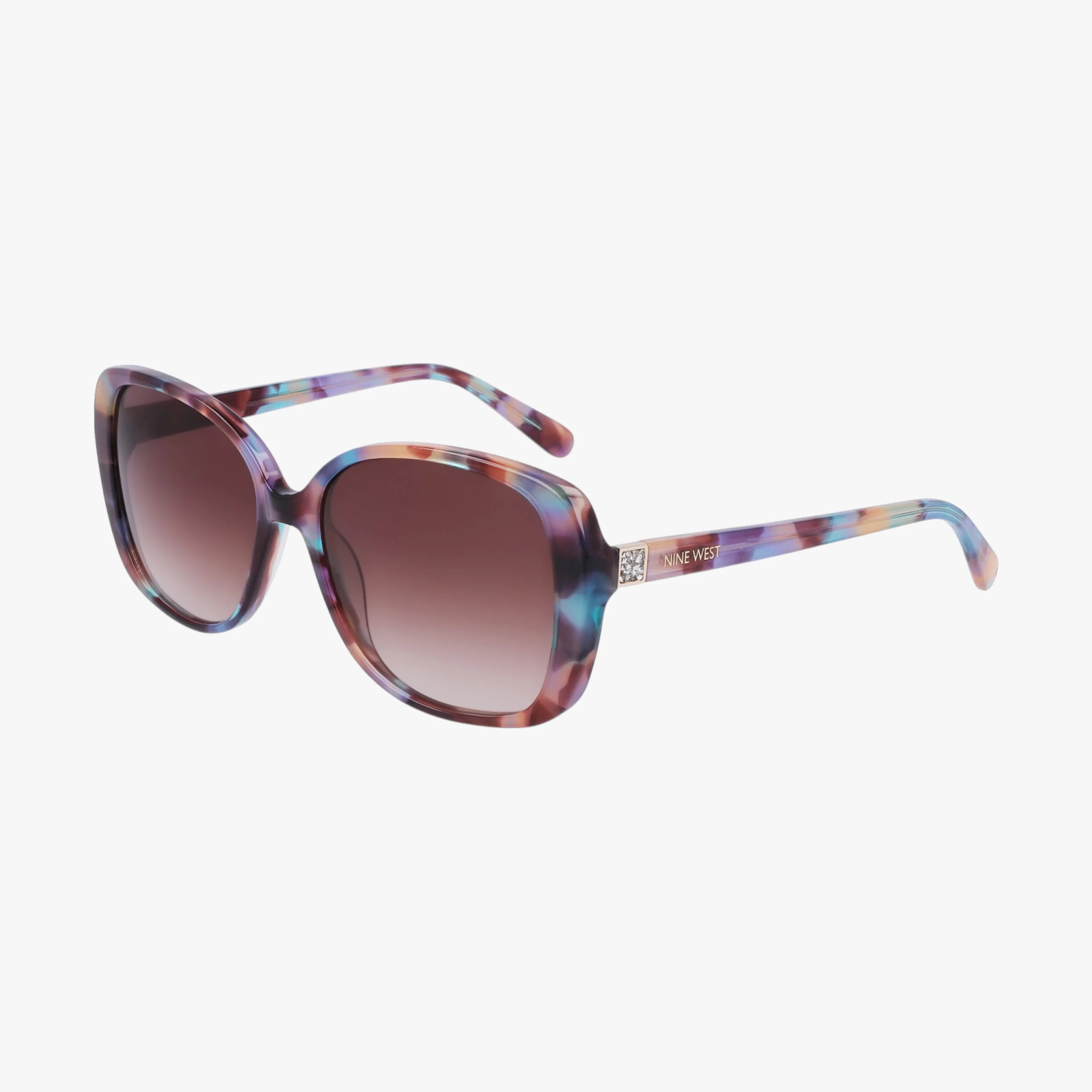 The NW657S cat-eye sunglasses feature multicolored oval frames in purple, blue, and brown marble with dark gradient lenses, a sturdy build, and a subtle metal logo detail near the left hinge, shown against a white background.