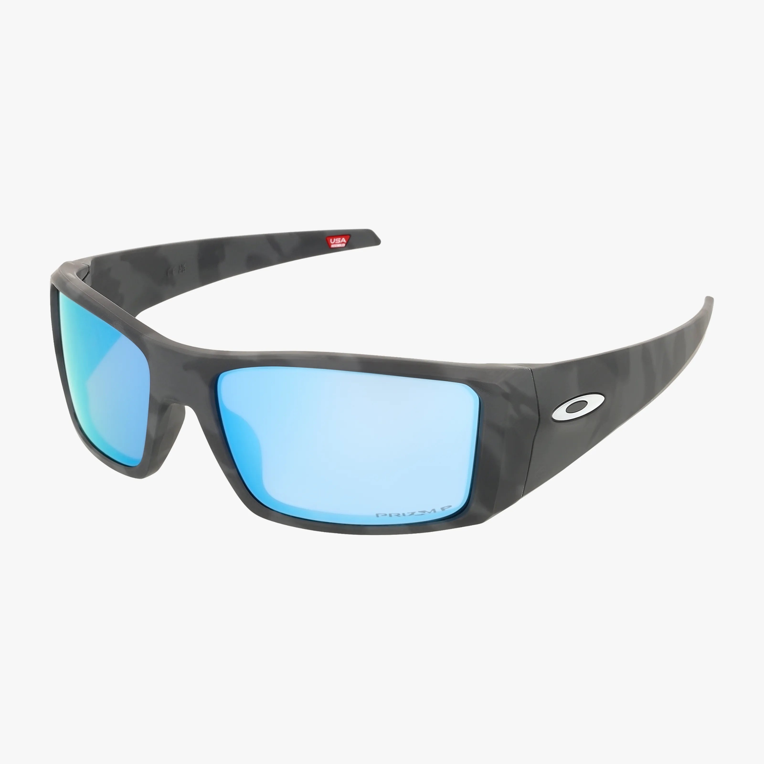 The OO9231 HELIOSTAT sunglasses feature a black wraparound frame, blue mirrored premium lenses, and a white Oakley logo on the arms, shown against a white background.